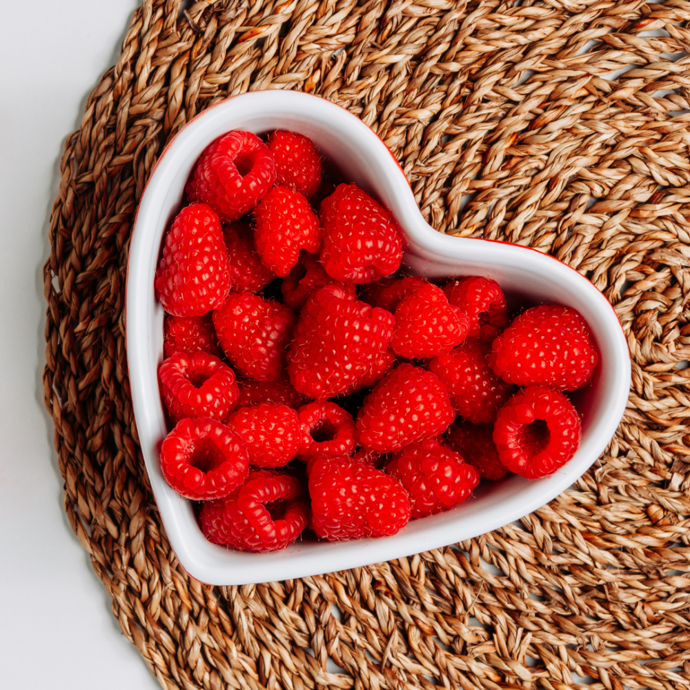 red raspberries in a heart-shaped bowl