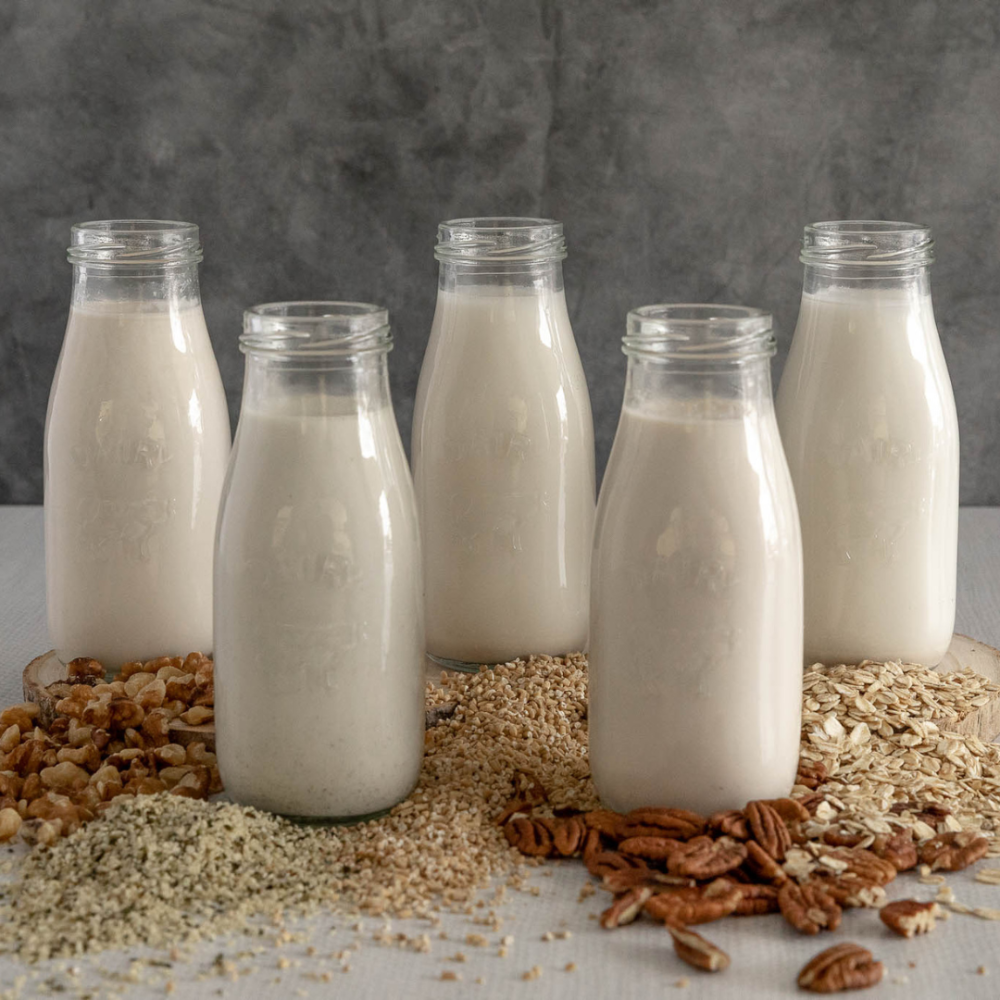 White juice in 5 glass bottles around brown seeds